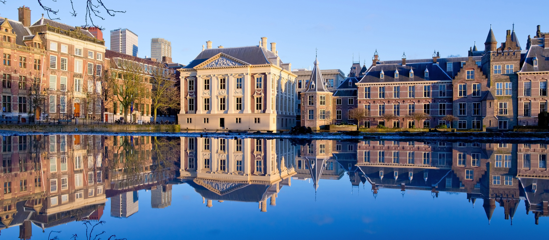 Historische gebouwen aan een waterkant met reflecties in het water in Den Haag, Nederland.